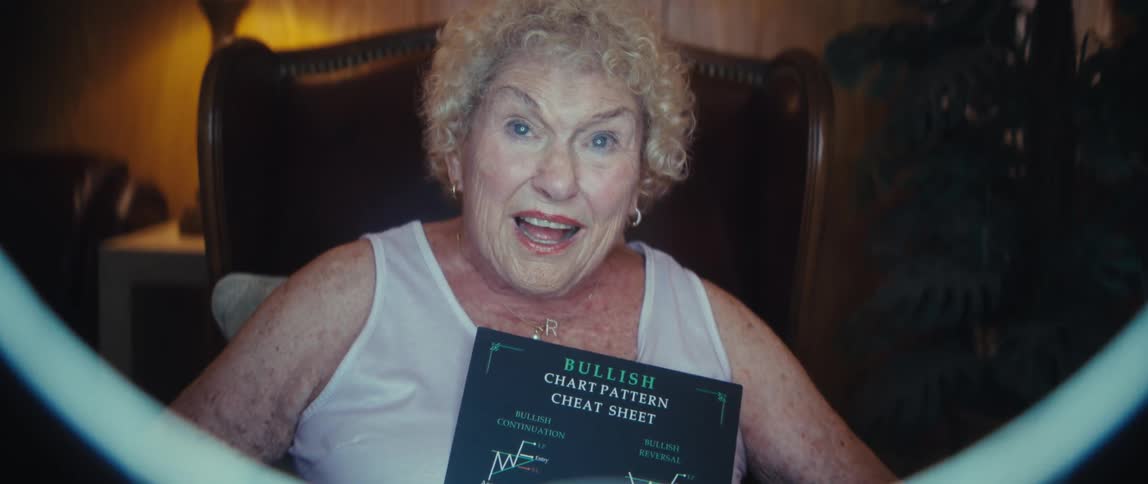Older woman holding a chart pattern sheet in front of a ring light in an indoor setting