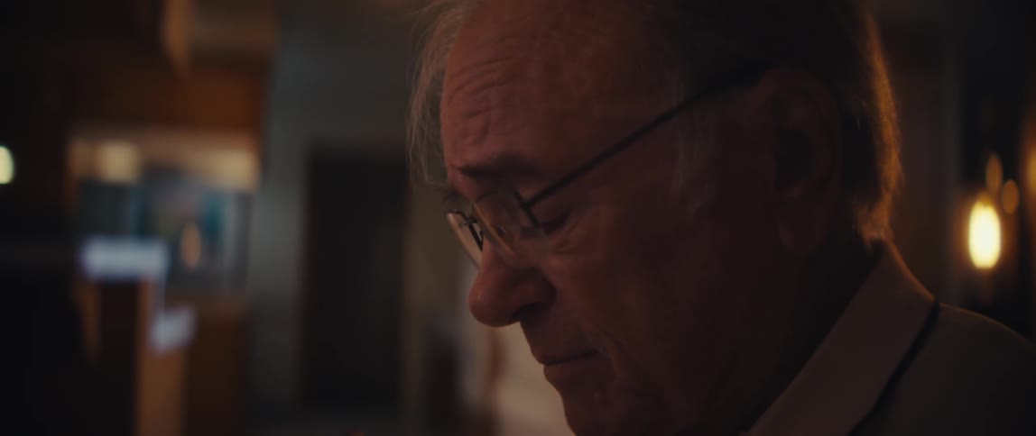 Elderly man taking notes while listening to a recording