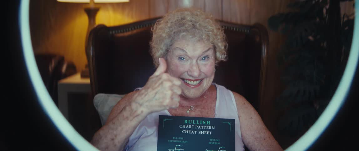 Older woman holding a financial chart in front of a ring light in an indoor setting