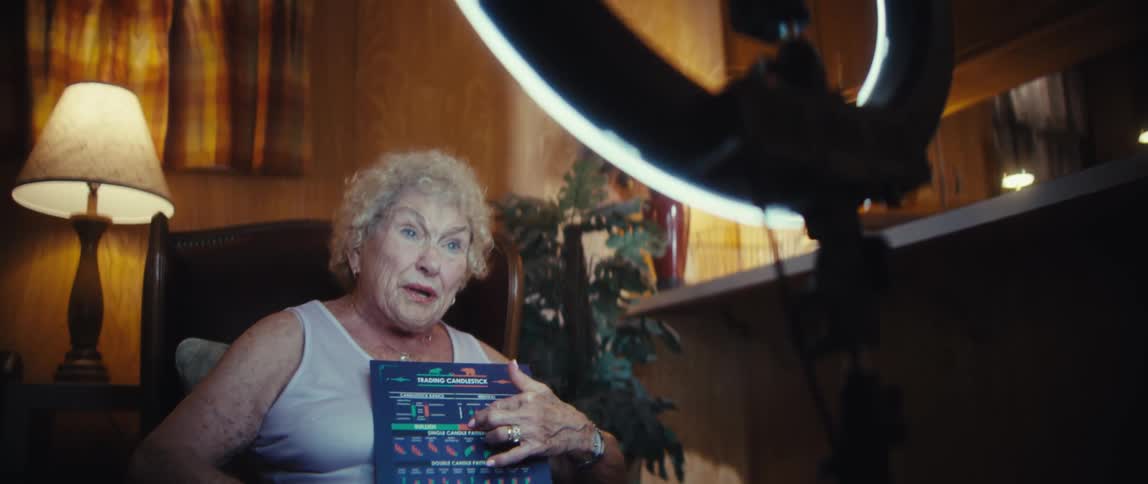 An elderly woman holds a pamphlet while sitting behind a camera giving an interview and sharing her views