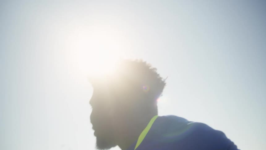 A male soccer or football player wearing a blue jersey with the number 11 and captain on the back is shown outdoors on a sunny day he is intensely focused and then appears to run or move toward the goal celebrating with a raised fist in a moment o