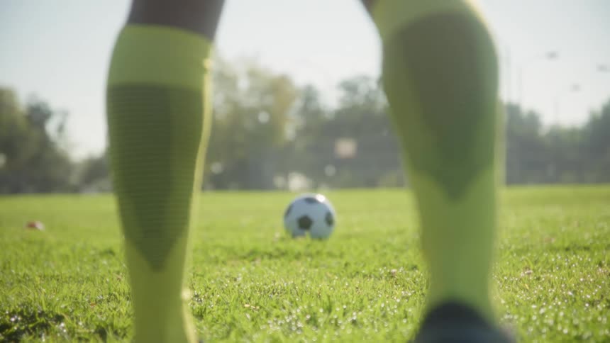 Player standing in front of a soccer ball on the grass