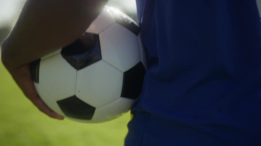 The man holds a soccer ball on the green field