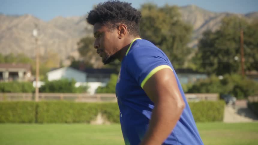 A young man in a cbz jersey trains alone on a sunny soccer field preparing for a match