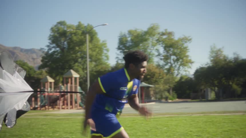 Athlete running in training with a resistance parachute on an open field