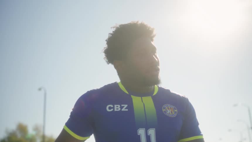 Soccer player holding a ball on a sunlit field