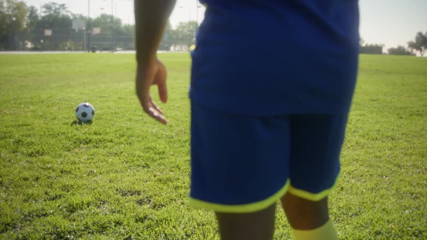 Close up of a young black male soccer player standing at a soccer training field during daytime