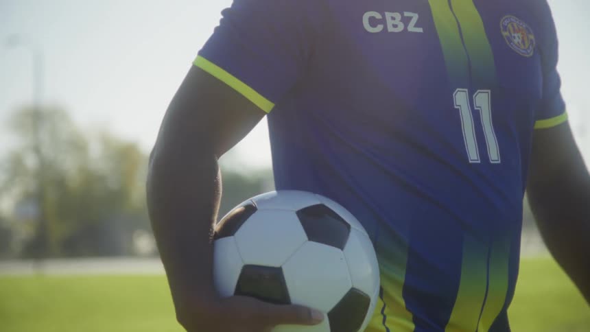 A man walking outdoors with a soccer ball