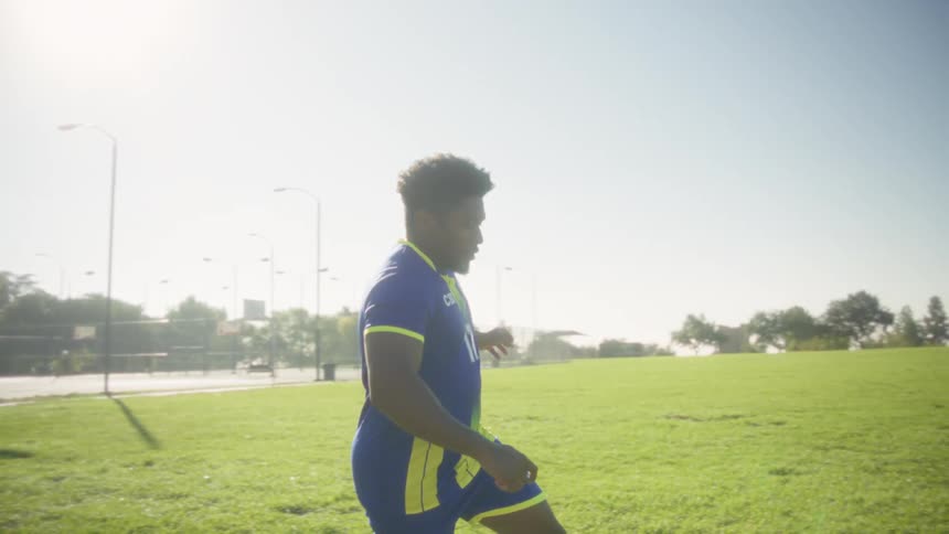 Player dribbling the ball between cones during training on a sunny field