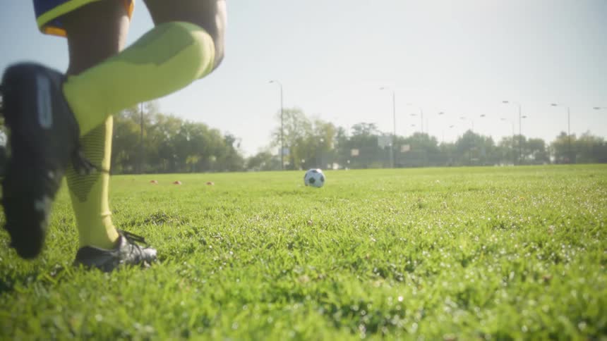 Player running toward the ball on a sunlit grass field