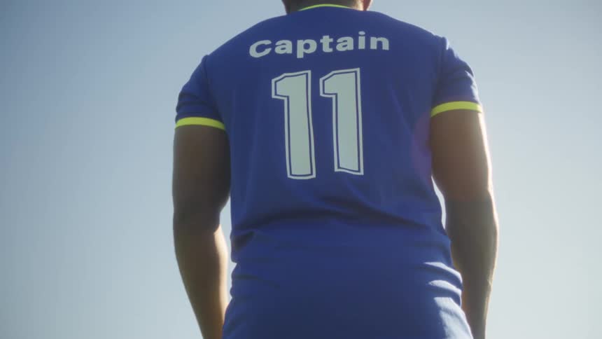 A young black male soccer player standing on a field in preparation for a training session during daytime