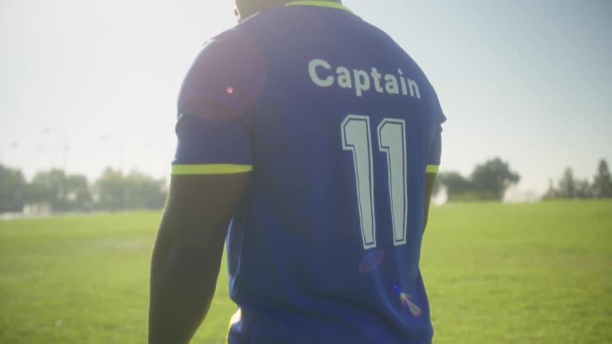 Soccer team captain stands in a field on a summer day and stares