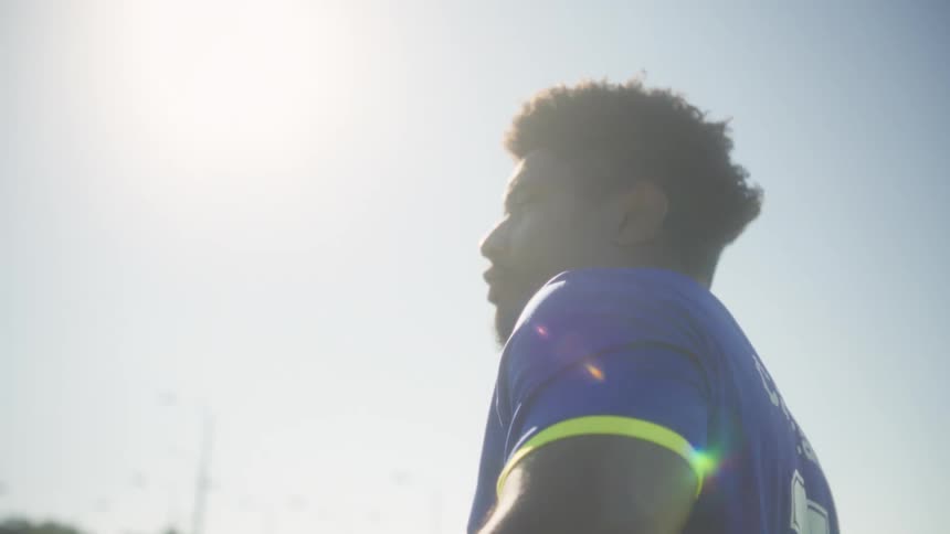 A man walking outdoors with a soccer ball