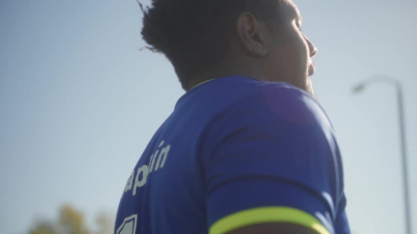 A soccer player stands on a football field under the sunny sky wearing a jersey with 11 and captain printed on the back