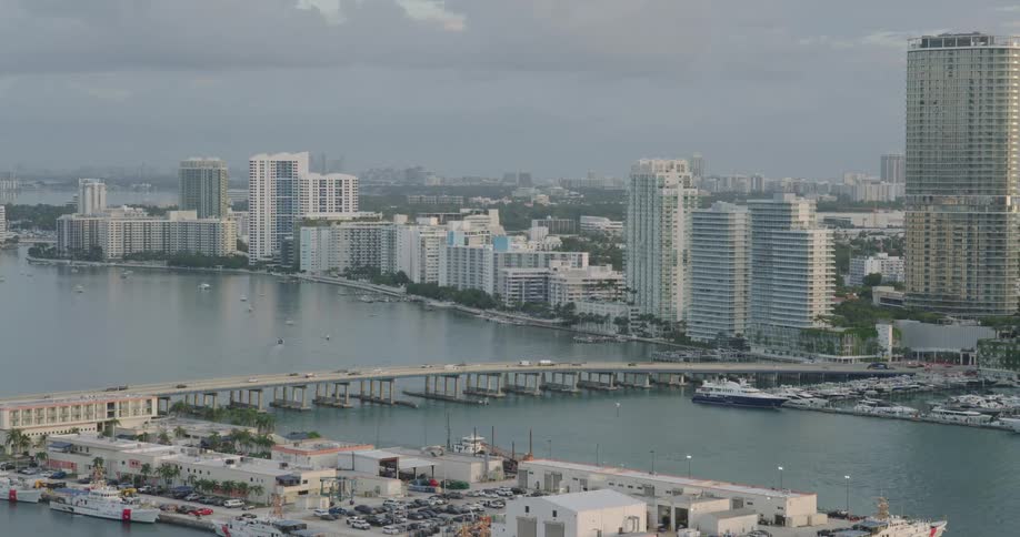 Coastal cityscape with tall buildings a marina and a bridge over the water