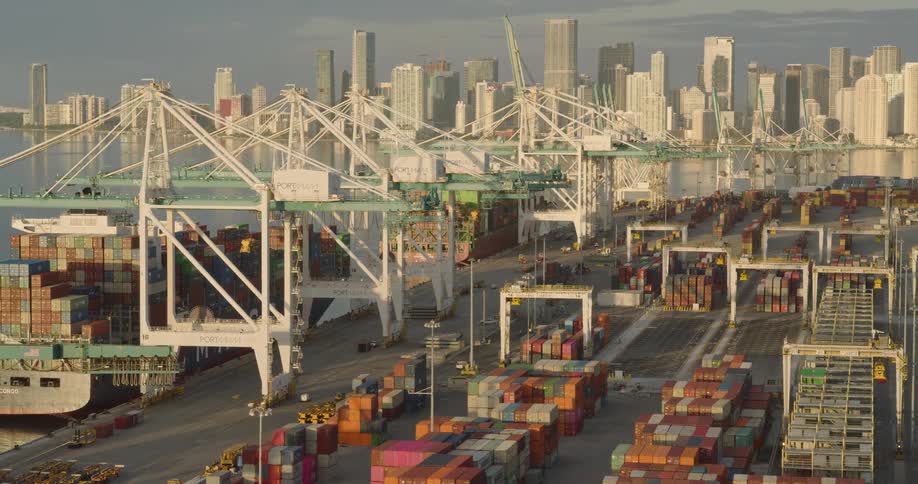 Container port with cranes and stacked containers with buildings in the background