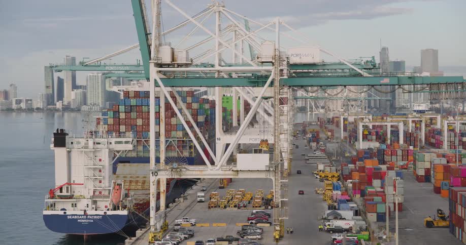 Container ship docked at a terminal with cranes and a yard full of containers