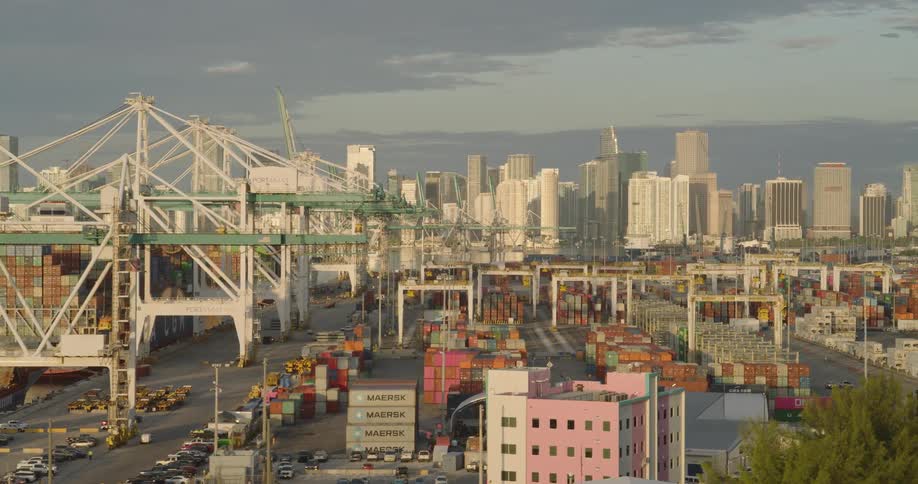 Cargo terminal with cranes and containers in front of an urban skyline