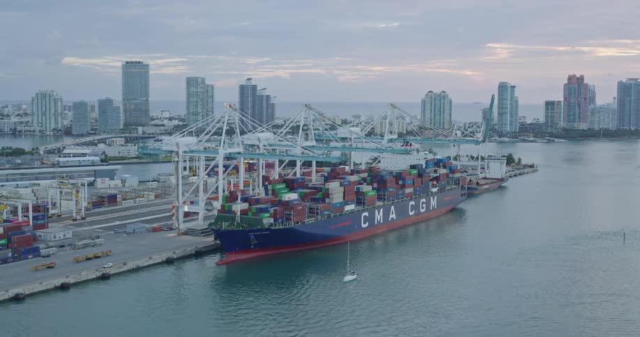 Container ship docked at a terminal surrounded by coastal skyscrapers