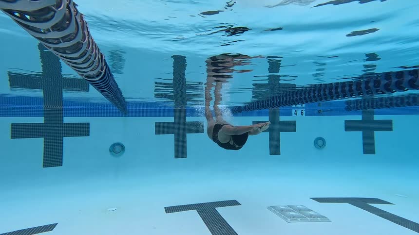 Swimmer moving underwater in a pool lane