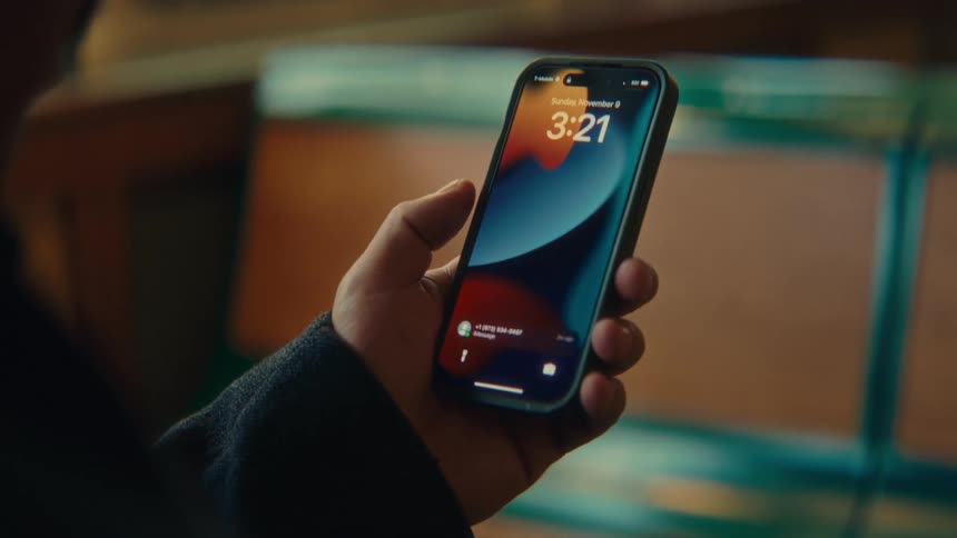 Hand holding a smartphone showing the lock screen with a call notification