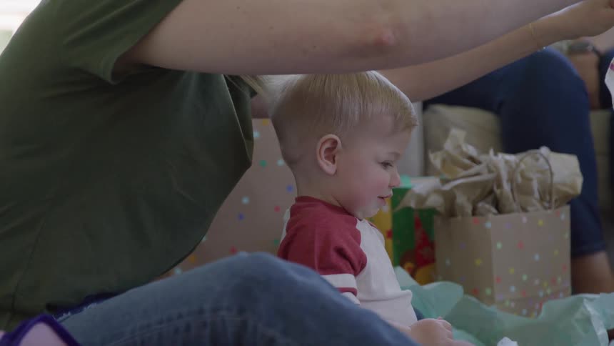 Child sitting beside an adult while holding colorful gift items