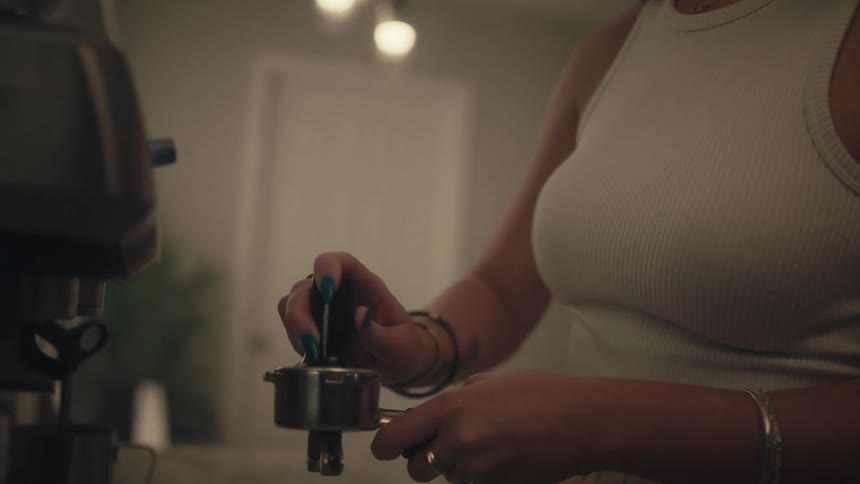 Woman preparing a coffee machine portafilter in an indoor setting