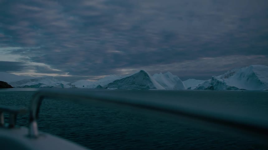 A boat approaching the coast on a frozen artic area outdoors during dusk or dawn