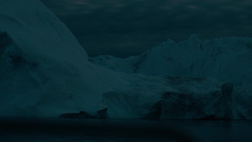 Massive jagged icebergs loom over dark waters in the fading twilight drifting slowly as the cold ocean laps against their frozen bases