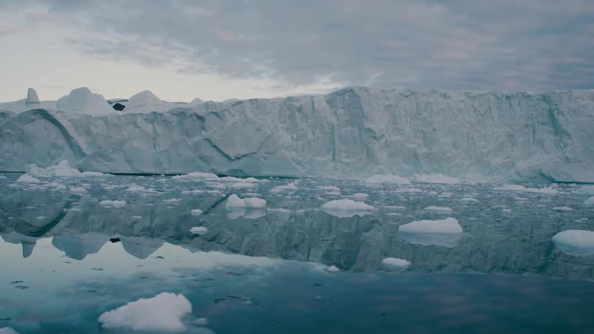 Glacier and pieces of melting ice floating away on arctic water