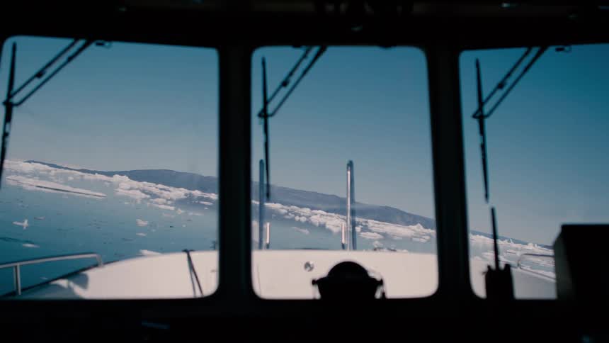 Boat with multiple windshield wipers moves between floating ice on a winter day