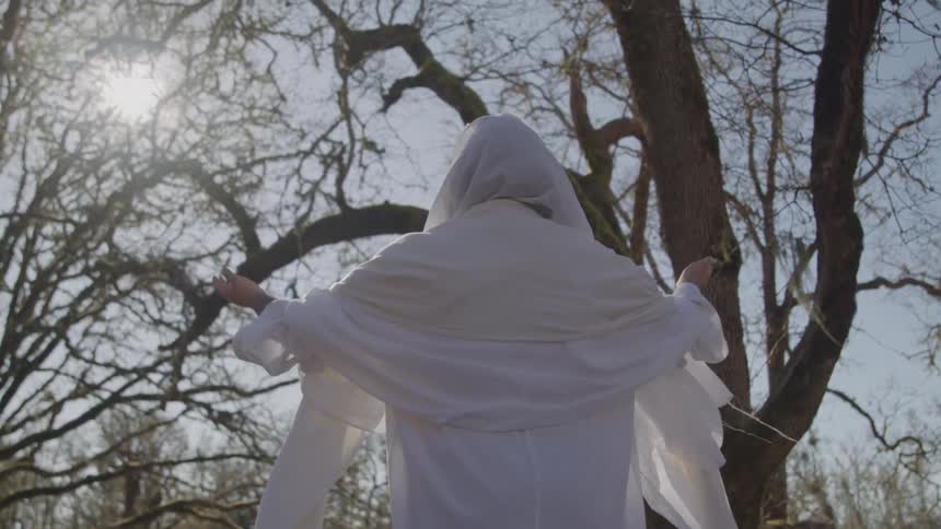 A woman in a white dress raising her arms