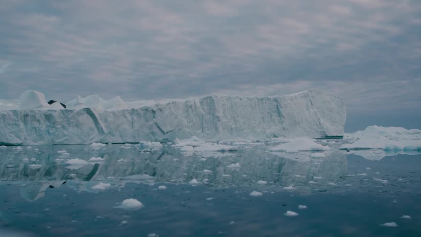 Glacier reflects on the arctic water as melting ice floats away