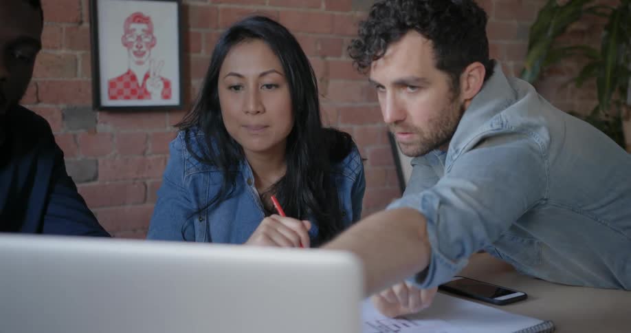 A man points at a computer while a woman watches