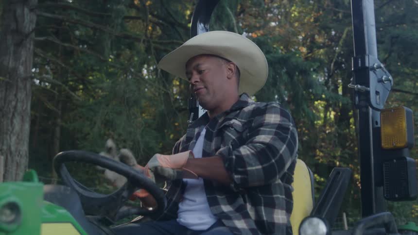 Man wearing a hat and gloves sitting on agricultural machinery