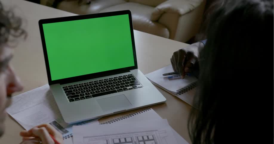 Three people sit at a table together with a laptop