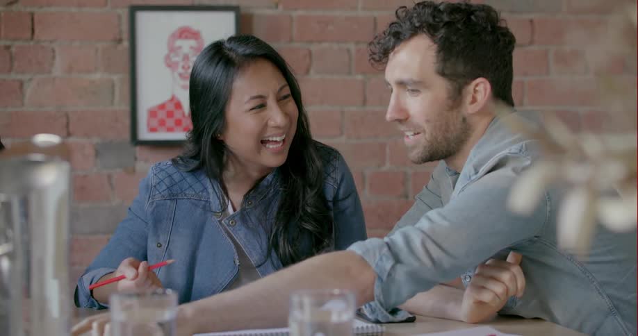 A man and woman laugh while working