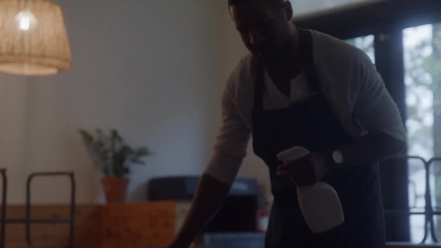 The worker is cleaning the table in the restaurant