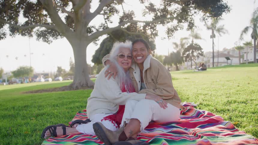 Portrait of an elderly woman hugging a young woman while at an outdoor picnic during daytime
