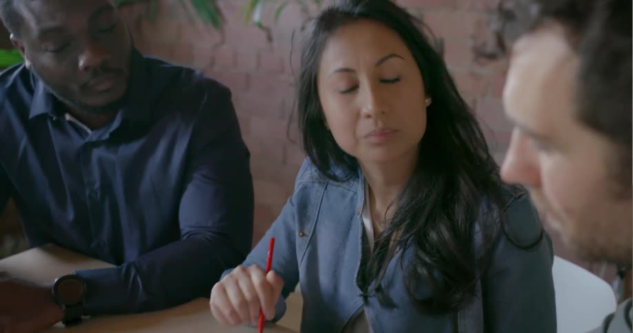 People sit at a conference table examining a blueprint