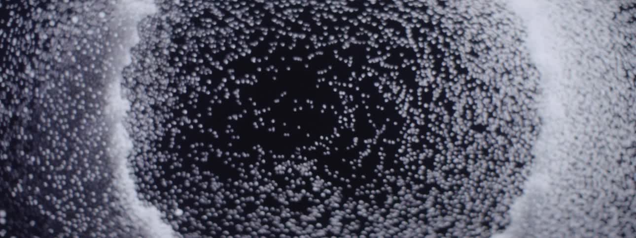 abstract dark circular void gradually filling with anamorphic particles