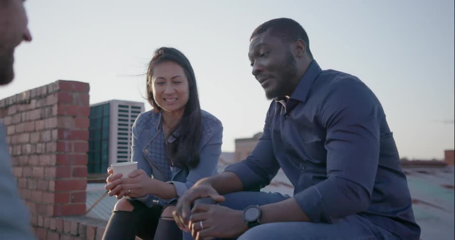 Man and woman sit on a roof talking