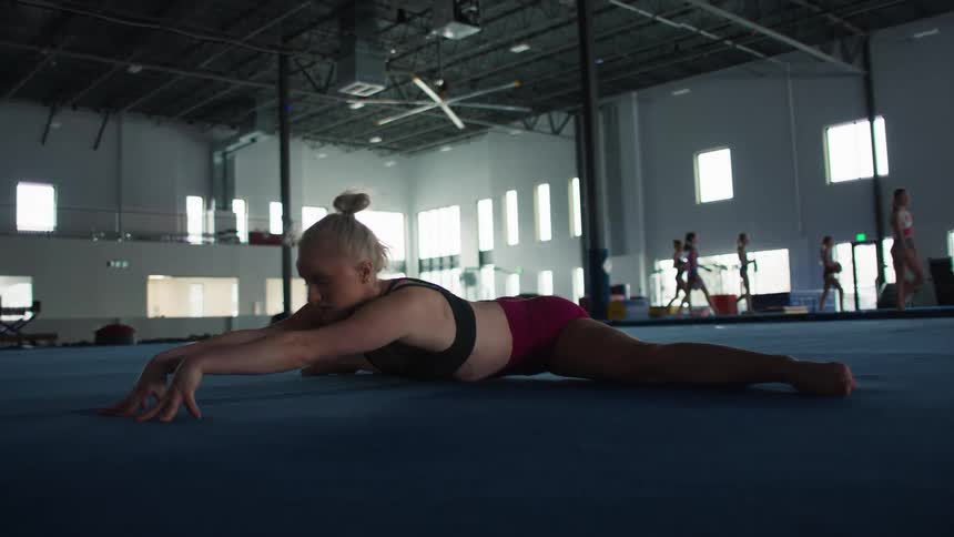 Gymnast performing a floor stretch inside a sports gym