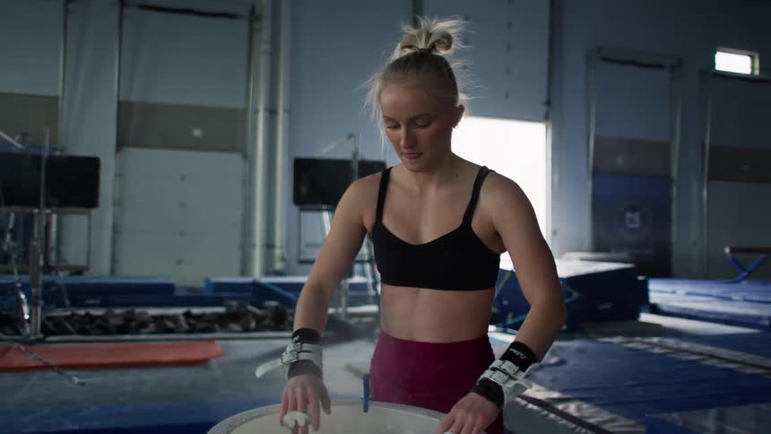 A gymnast in a gym is putting powder on her hands