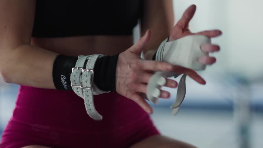 Young woman tying straps to her hands at the gym indoors during day time