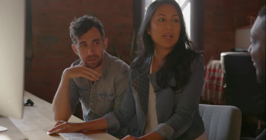 Men and woman talk and look at a computer monitor
