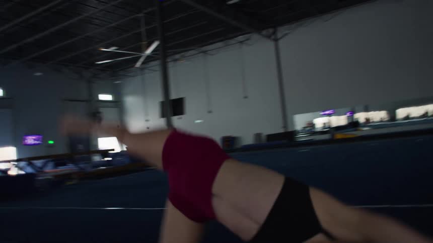 Gymnast in motion with arms raised inside a sports gym