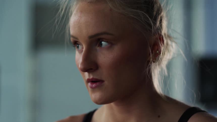 A woman from the shoulders up is breathing heavy and appears nervous as she looks forward