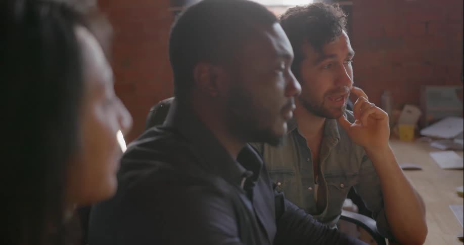 A man uses a computer while talking with people