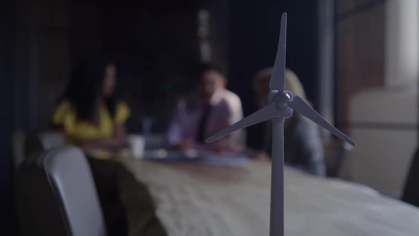 Wind turbine model placed on a table with people gathered in the background